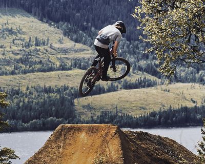 A mountain biker with a hydrationpack does a stunt.