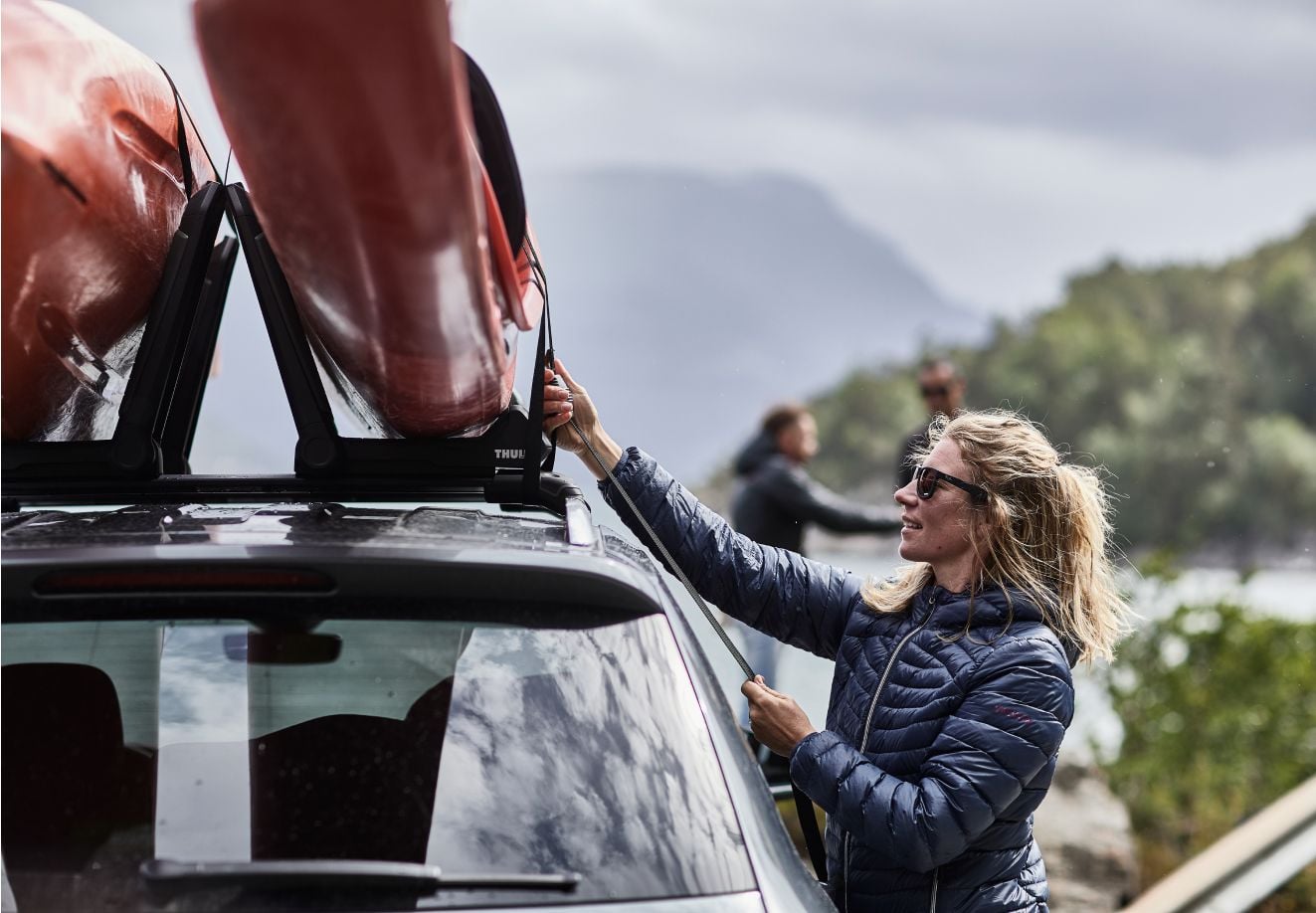 車の上にあるThuleカヤックラックにカヤックを固定する人。