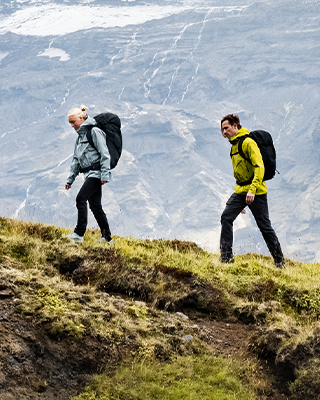 Dos personas caminando por un sendero de madera con mochilas de senderismo Thule.