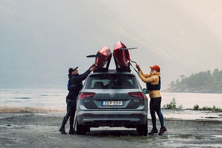 Zwei Personen beladen ein Auto mit zwei Kajaks im Nebel.